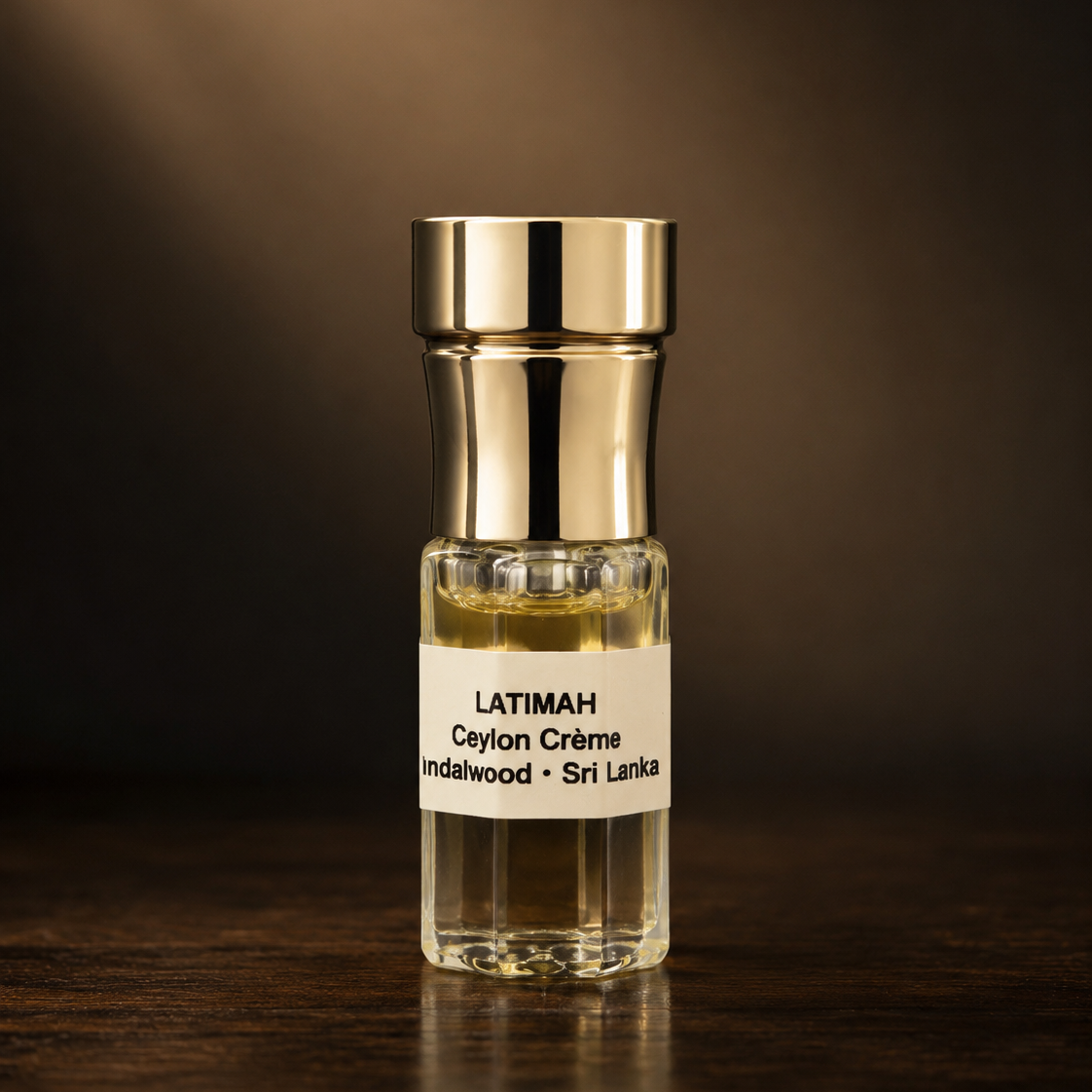 Small glass bottle with gold cap on a dark surface, featuring the brand 'LATIMAH'.